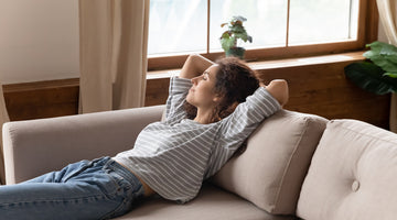 Contented woman relaxes on couch enjoying the benefits of the positive side effects of CBD