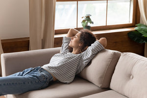 Contented woman relaxes on couch enjoying the benefits of the positive side effects of CBD